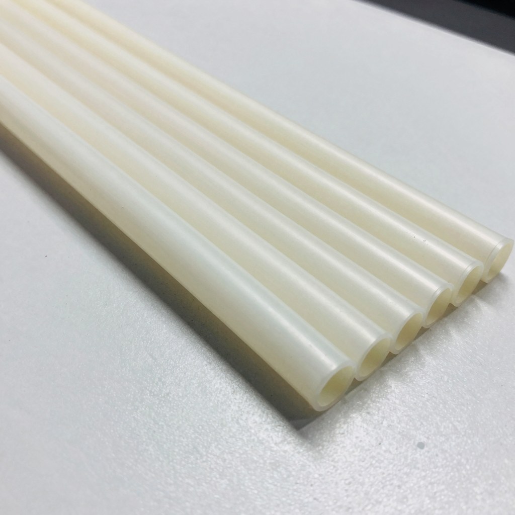 Photorealistic cut-to-length fluoropolymer tubing pieces neatly aligned in rows, precision cut ends, clean production inspection table, no text, no logo, no watermark